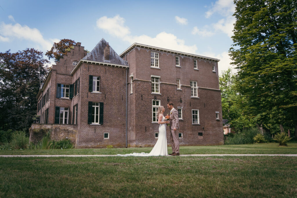 Bruidspaar op het gazon voor een kasteel