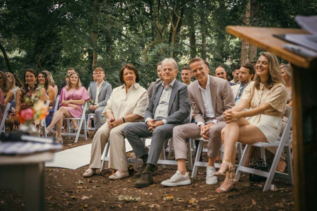 Gasten zitten aandachtig te kijken tijdens een buitenceremonie